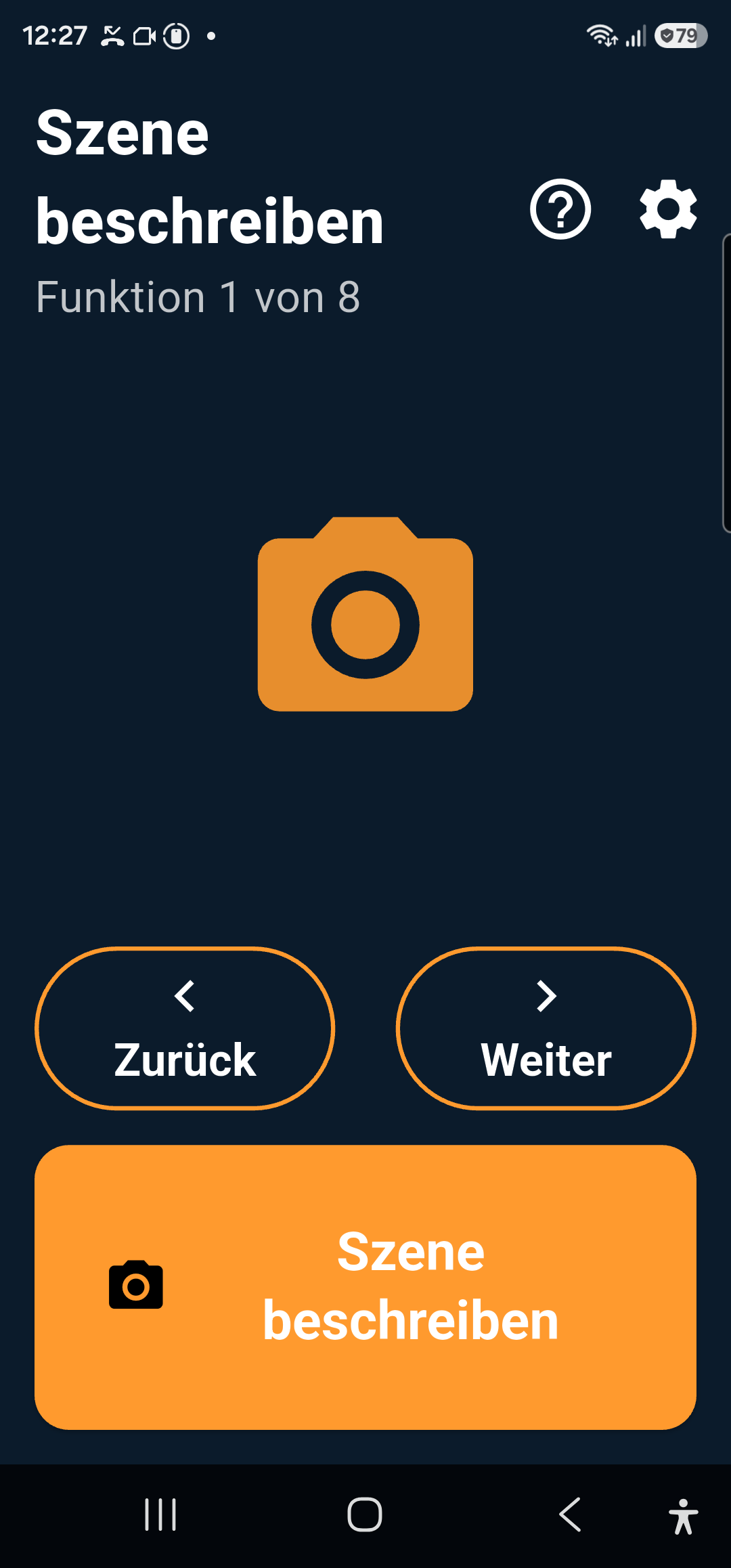 Screenshot der App 15/15 Sehen: Funktion 1 von 8 &bdquo;Szene beschreiben&ldquo;, großer oranger Auslöse-Knopf, Zurück/Weiter-Knöpfe. Hoher Kontrast, dunkler Hintergrund, große weiße Schrift.